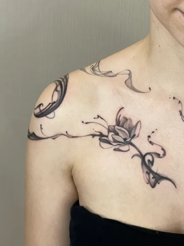 Floral tattoo with flowing ornamental lines across the shoulders