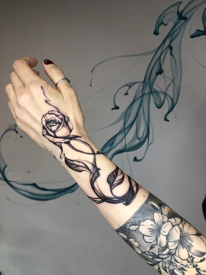 Rose tattoo with flowing lines on the hand and wrist
