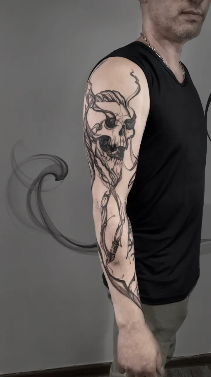 Skull and abstract linework tattoo along the arm
