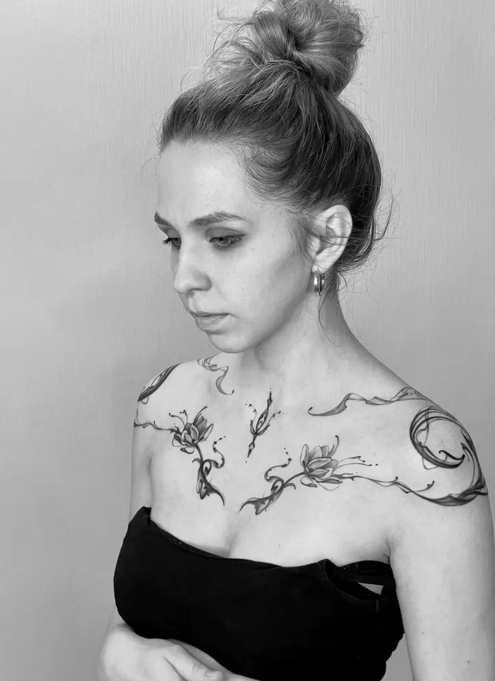 Floral tattoo with flowing ornamental lines across the shoulders