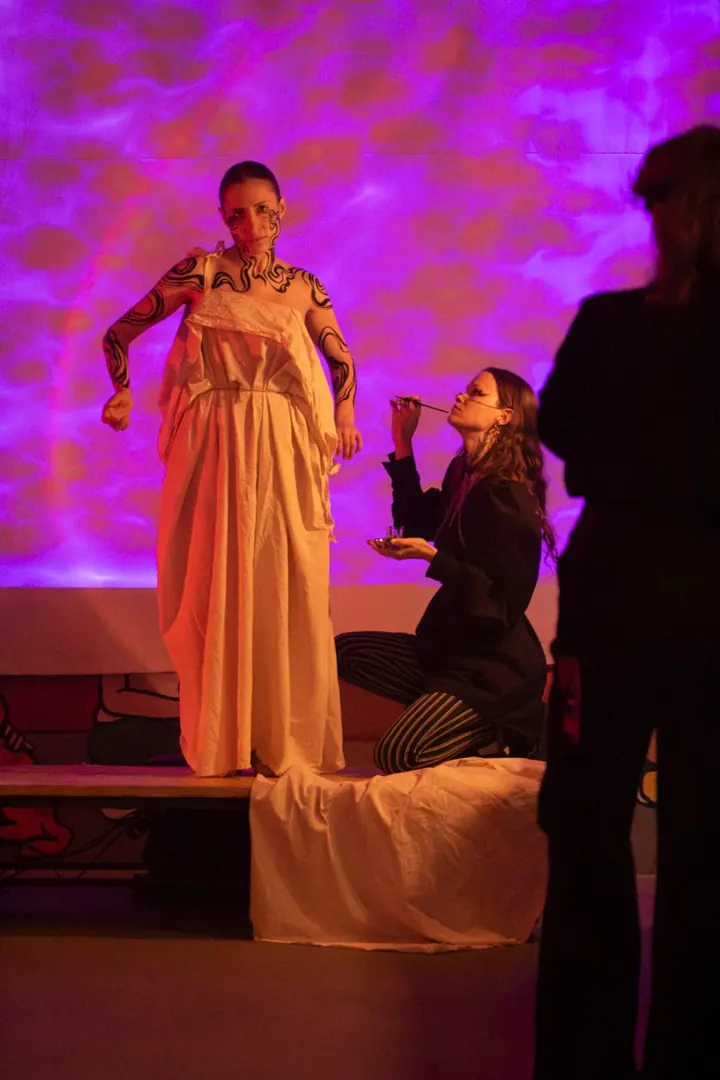 Body-painting performance under violet and pink light
