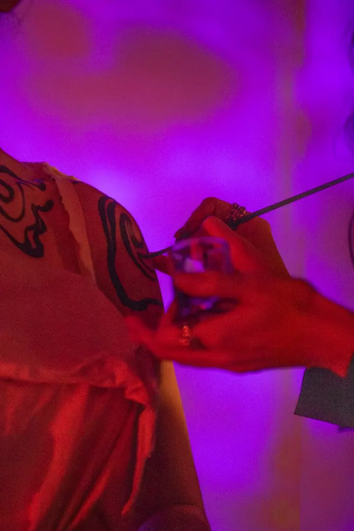 Body-painting performance under violet and pink light