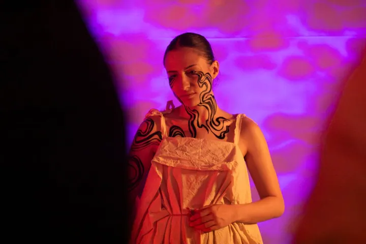 Body-painting performance under violet and pink light