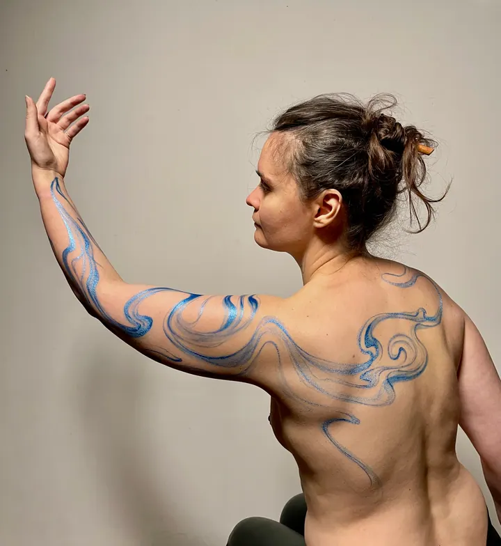 Flowing blue body painting across the back and arm