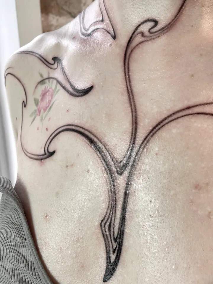 Abstract linework tattoo across the neck, shoulders and chest