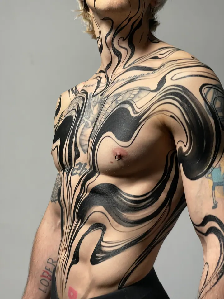 Flowing black body painting across a tattooed model’s torso