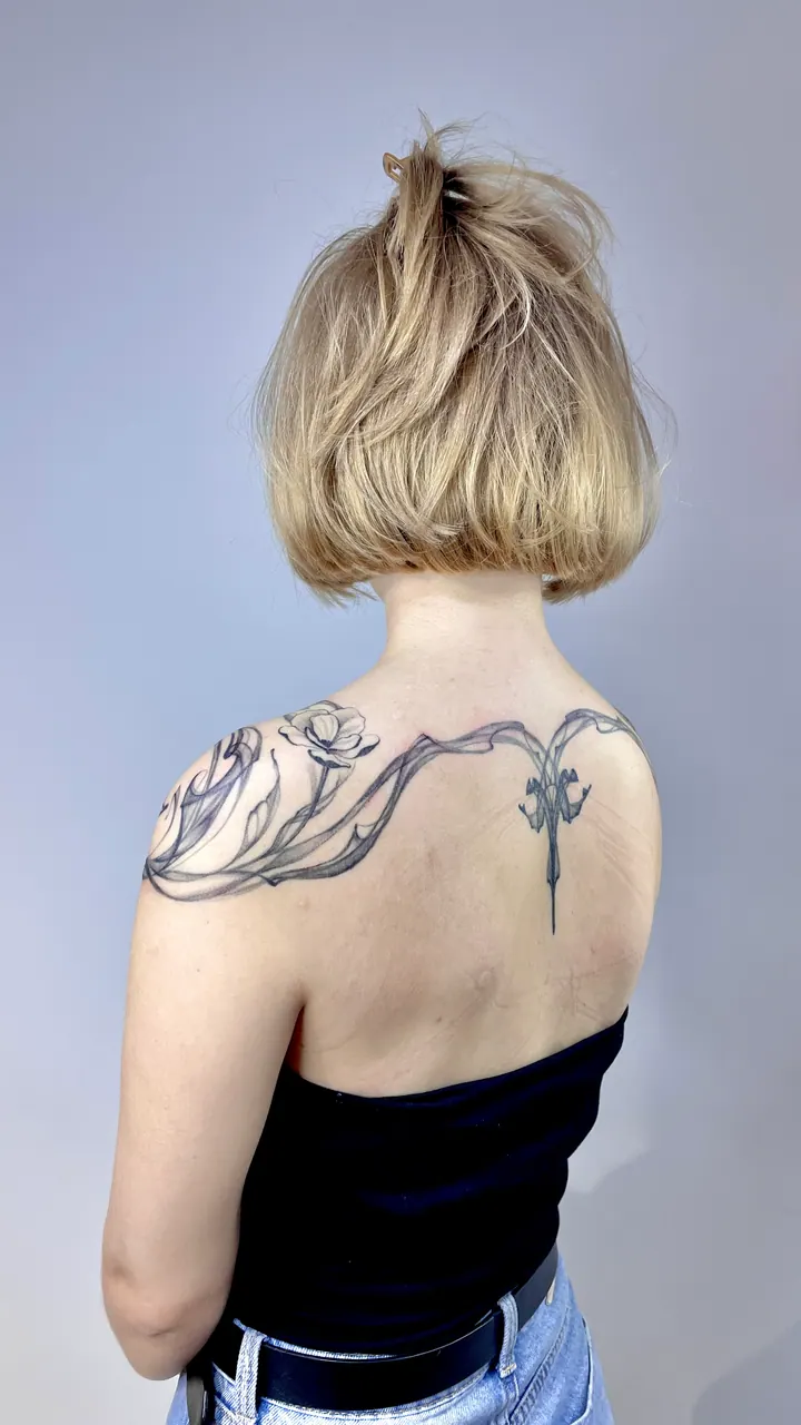 Floral tattoo with flowing ornamental lines across the shoulders