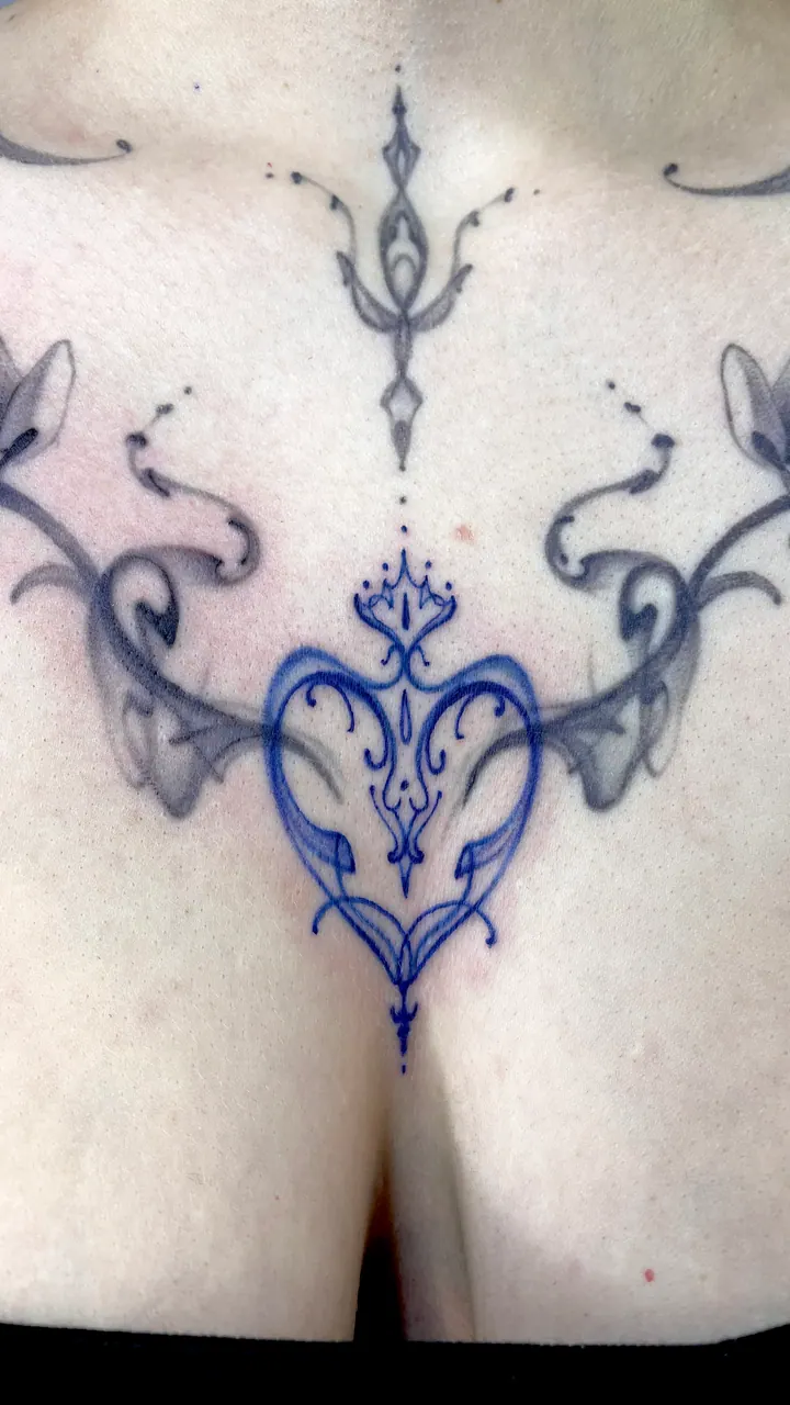 Floral chest tattoo with a blue heart design stencil
