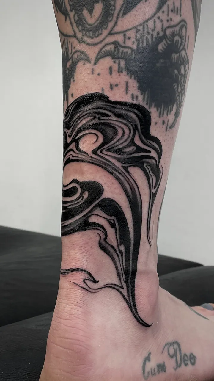 Flowing blackwork tattoo around the ankle