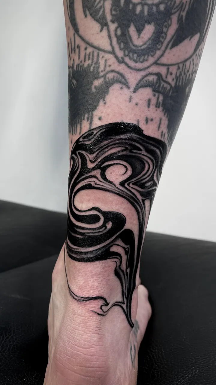 Flowing blackwork tattoo around the ankle