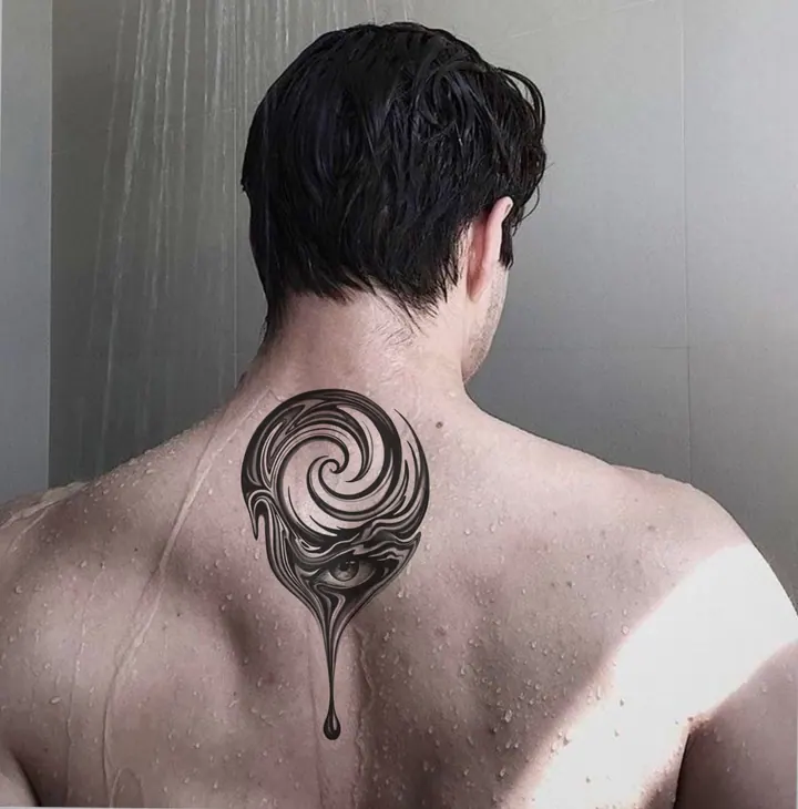 Spiral and eye tattoo design shown on the upper back