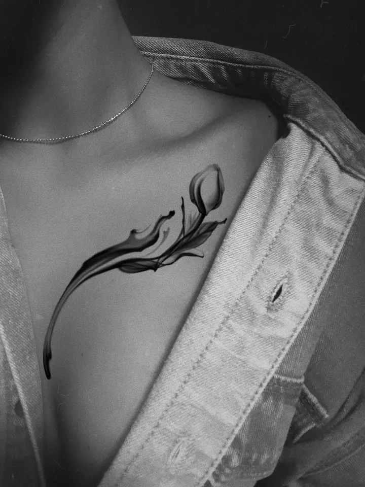 Flowing flower tattoo design shown below the collarbone